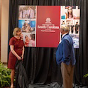 two people unveil a banner