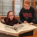 two students looking at a very large old book