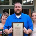 Albert Robinson holding up aplaque, flanked by two other teachers