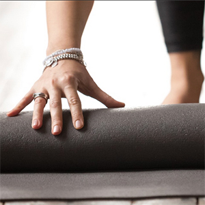 Crop of hand unrolling yoga mat for a workout