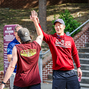 A coach high fives a student runner.