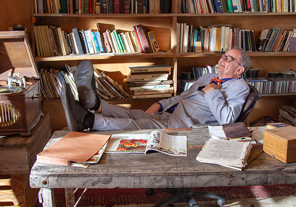 David Shields sits behind a desk on the set of Savers of Flavor.